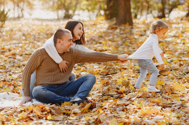 Linda y elegante familia jugando en un campo de otoño