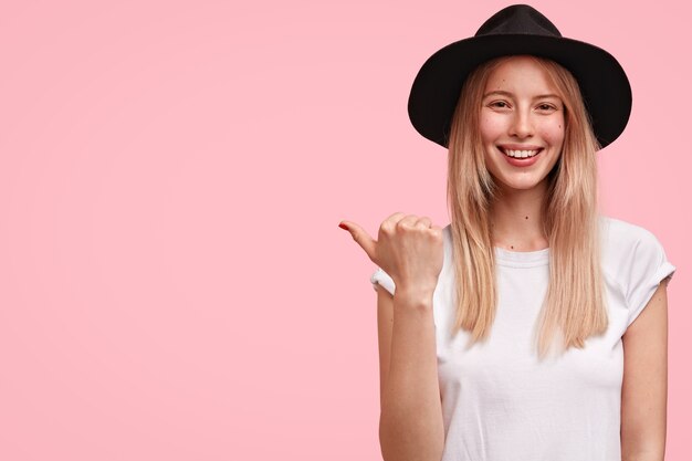 Linda elegante joven mujer europea vestida con camiseta blanca y viste sombrero negro