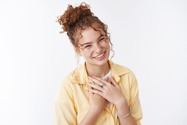 Linda encantadora tierna estudiante europea de jengibre, moño rizado y desordenado, corte de pelo, pecas, riendo felizmente, sonriendo, ruborizado, prensa, palmas, pecho, tocado, sentirse agradecido, apreciando la ayuda, fondo blanco