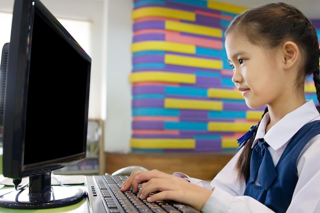 Una linda estudiante asiática que usa una computadora en la escuela con una pantalla en blanco