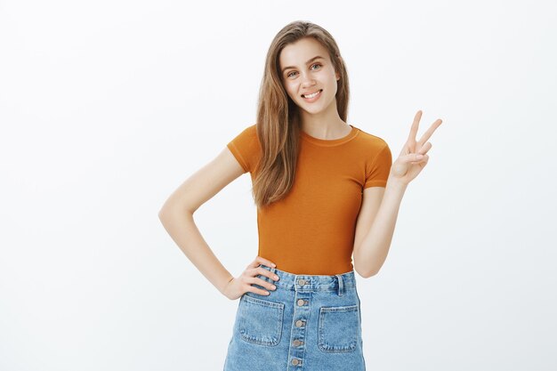 Linda estudiante joven sonriente mostrando gesto de paz