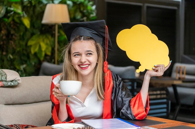 Linda estudiante rubia sosteniendo un tablero de ideas y bebiendo café