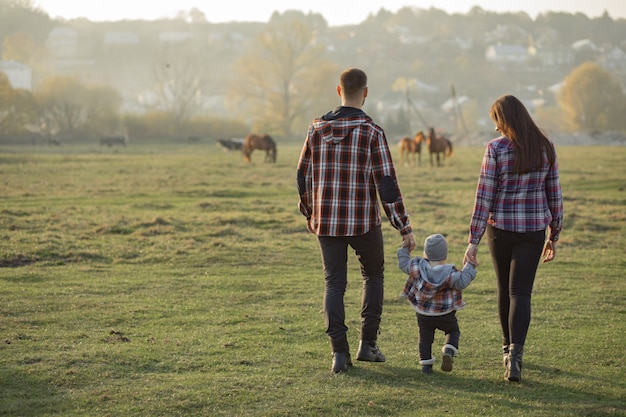 Linda familia caminando en un parque de verano al atardecer