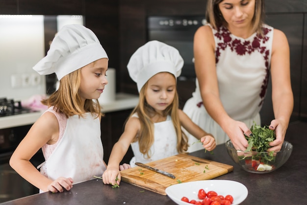 Linda familia en cocina preparando ensalada saludable en encimera de cocina