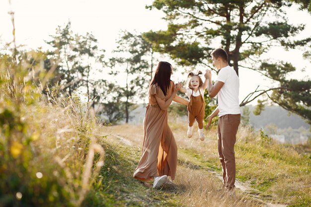 Linda familia jugando en un campo de otoño