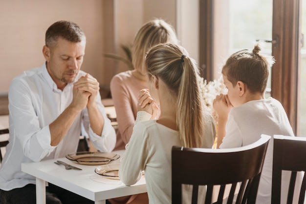 Linda familia rezando juntos antes de comer