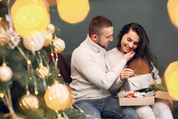 Linda familia sentada en casa cerca del árbol de navidad