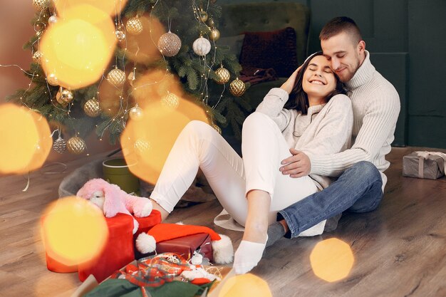 Linda familia sentada en casa cerca del árbol de navidad