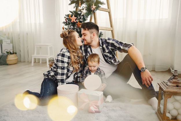 Linda familia sentada cerca del árbol de navidad