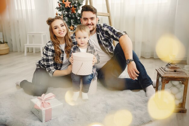 Linda familia sentada cerca del árbol de navidad