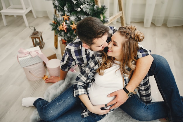 Linda familia sentada cerca del árbol de navidad