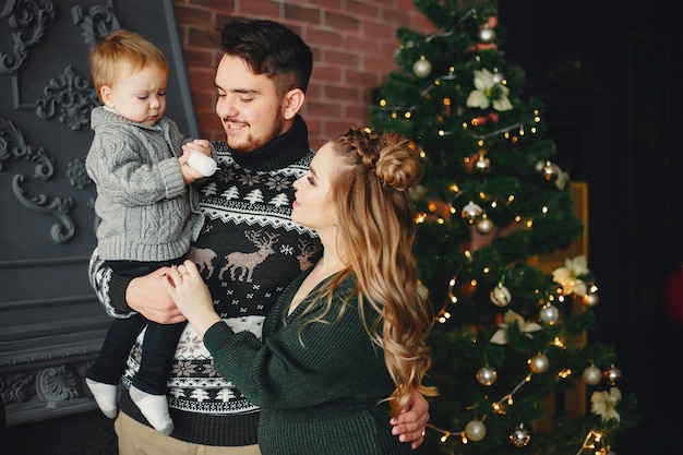 Linda familia sentada cerca del árbol de navidad