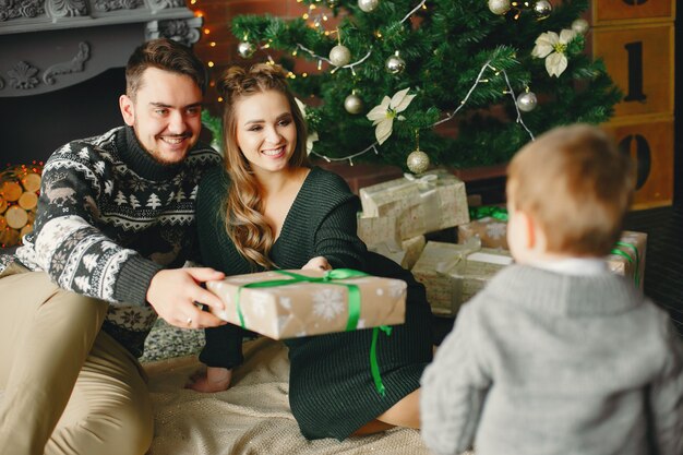 Linda familia sentada cerca del árbol de navidad