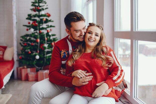 Linda familia sentada cerca del árbol de navidad