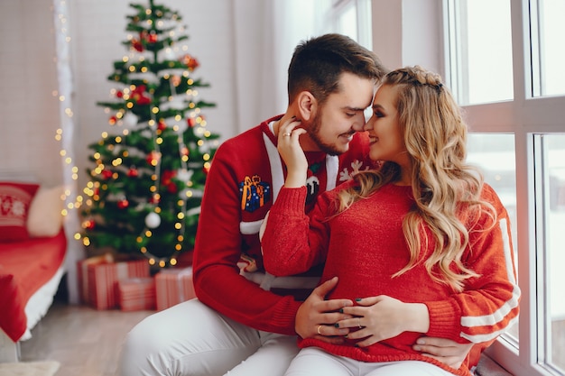 Linda familia sentada cerca del árbol de navidad