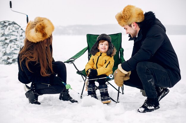 Linda familia sentada en una pesca de invierno con pequeño hijo