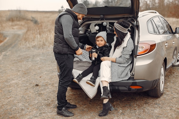 Linda familia tomando una bebida caliente en un campo de invierno