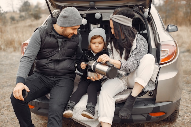 Linda familia tomando una bebida caliente en un campo de invierno