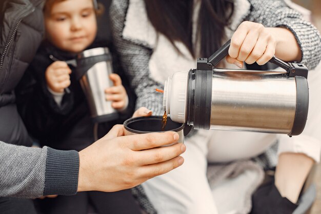 Linda familia tomando una bebida caliente en un campo de invierno