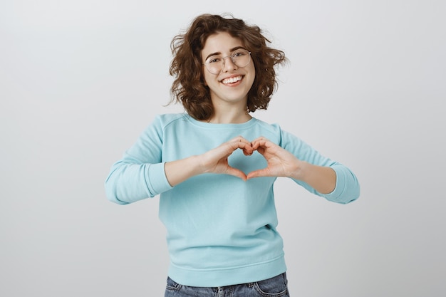 Foto gratuita linda y feliz mujer sonriente mostrando gesto de corazón sobre el pecho