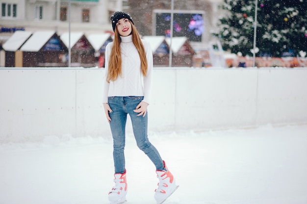 Linda y hermosa chica en un suéter blanco en una ciudad de invierno