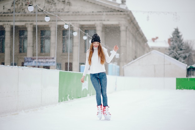 Linda y hermosa chica en un suéter blanco en una ciudad de invierno