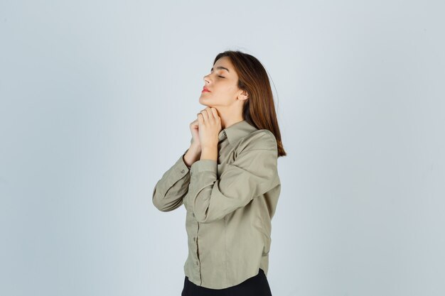 Linda joven mujer estrechando las manos en gesto de oración en camisa, falda y mirando esperanzado. .