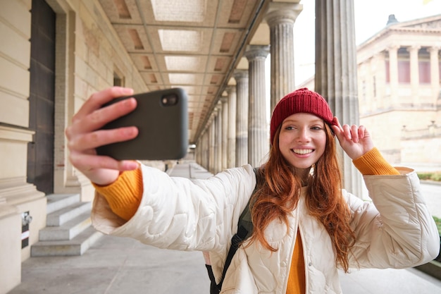 Linda joven pelirroja toma selfie en la calle con teléfono móvil hace una foto de sí misma con smar