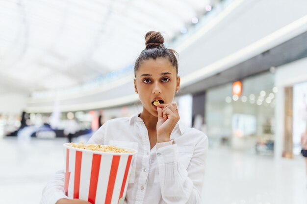 Linda joven sosteniendo palomitas de maíz en el centro comercial