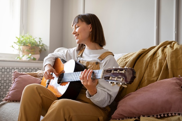 Foto gratuita linda joven tocando la guitarra en el interior