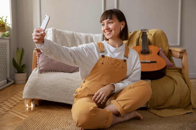 Foto gratuita linda joven tomando un selfie junto a su guitarra