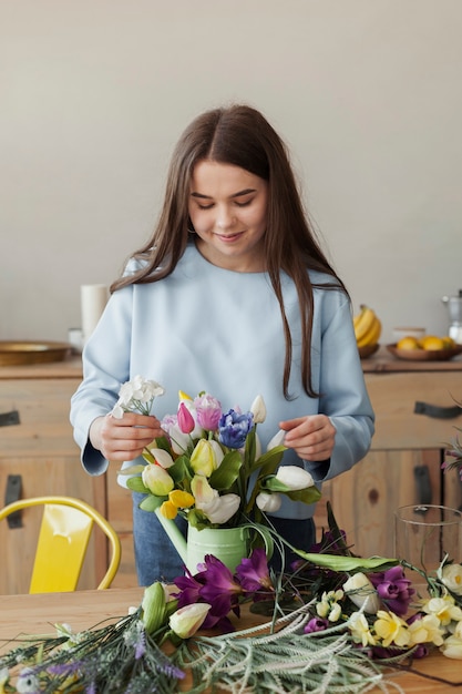 Linda jovencita ajustando un jarrón con flores