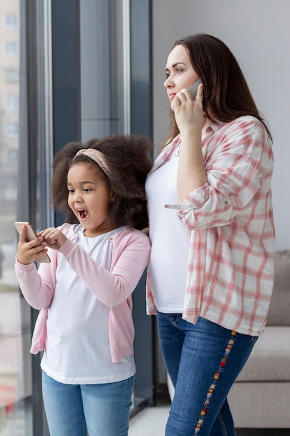 Foto gratuita linda madre hablando por teléfono junto a su hija