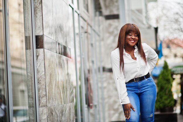 Linda modelo afroamericana en camisa blanca y pantalones vaqueros posó al aire libre