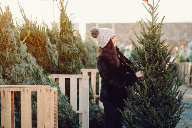 Linda morena en un suéter blanco con arbol de navidad.