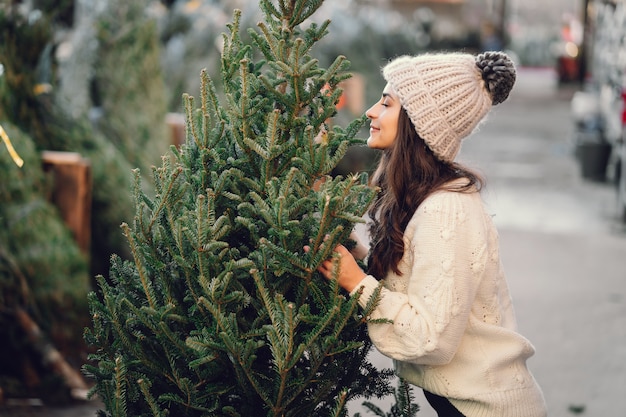 Linda morena en un suéter blanco con arbol de navidad.