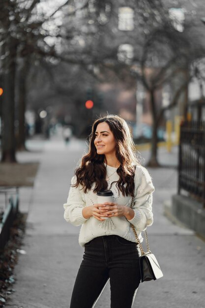 Linda morena en un suéter blanco en una ciudad