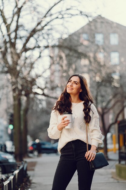 Linda morena en un suéter blanco en una ciudad