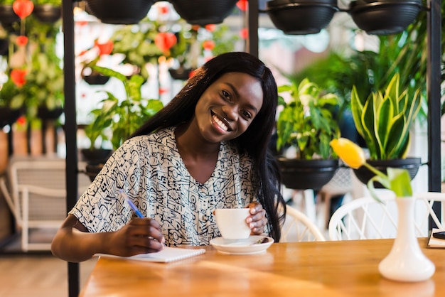 Linda mujer afroamericana agradable haciendo notas en el cuaderno