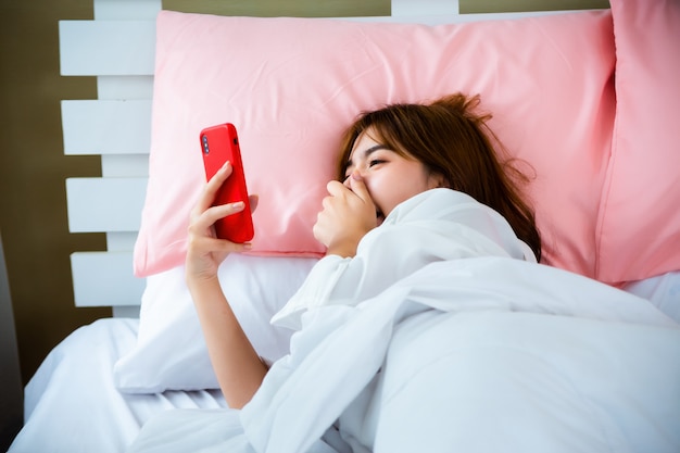 Linda mujer alegre con smartphone en dormitorio