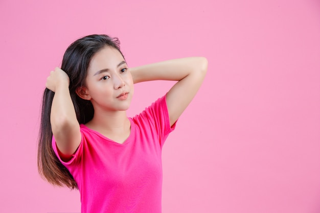 Linda mujer asiática blanca se posa con un cabello rosado en un rosa.