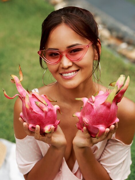 Linda mujer asiática con frutas de dragón rosa en manos