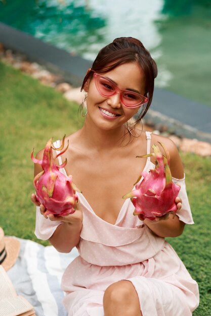 Linda mujer asiática con frutas de dragón rosa en manos