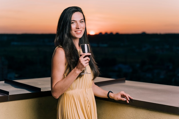 Linda mujer bebiendo vino en la azotea al amanecer