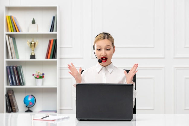 Linda mujer bonita de servicio al cliente con camisa blanca con auriculares y computadora sorprendida