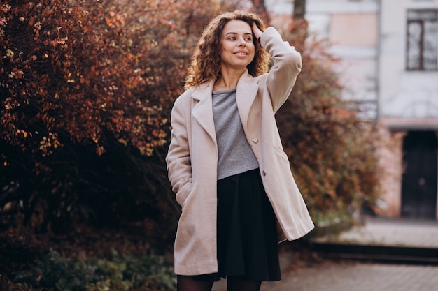 Linda mujer con cabello rizado caminando en un abrigo de otoño