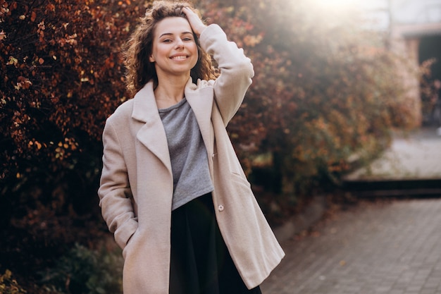 Linda mujer con cabello rizado caminando en un abrigo de otoño