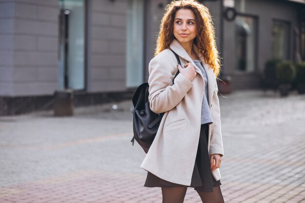 Linda mujer con cabello rizado caminando en un abrigo de otoño