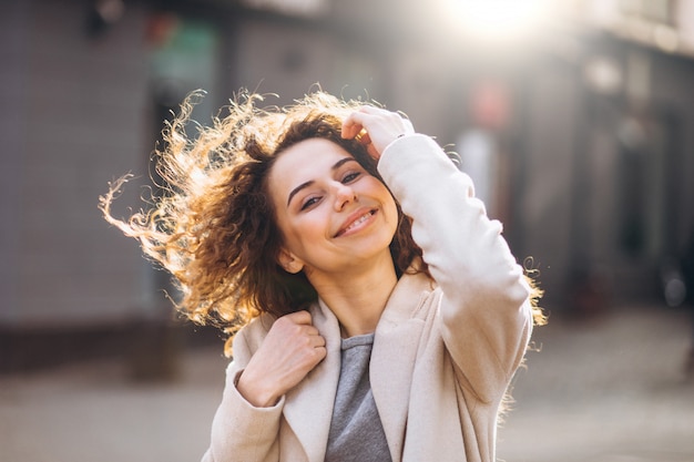 Linda mujer con cabello rizado caminando en un abrigo de otoño