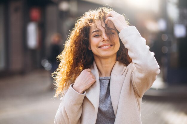 Linda mujer con cabello rizado caminando en un abrigo de otoño